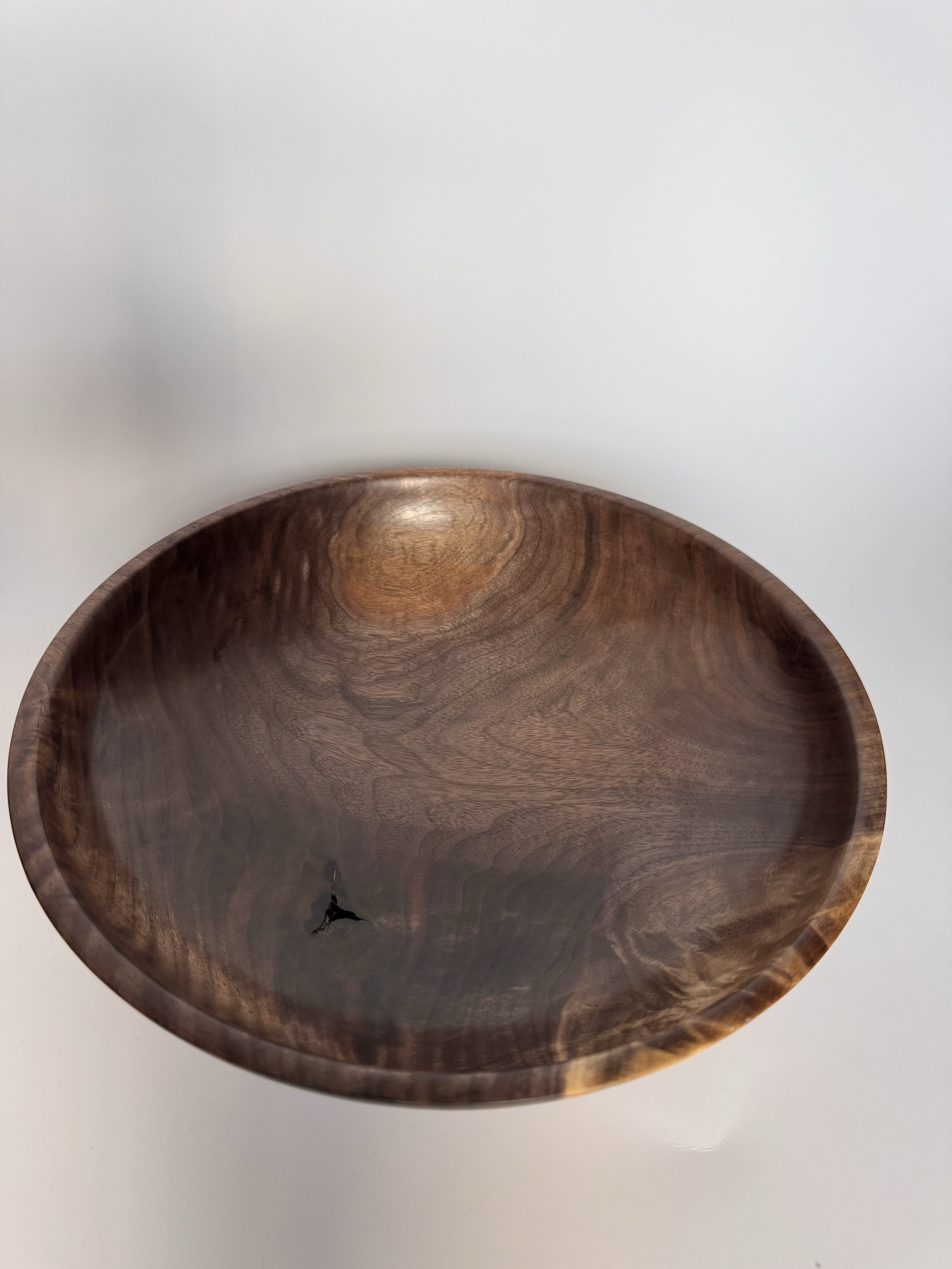 Interior view of low black walnut bowl showing dark grain, lighter figure, and a small natural inclusion