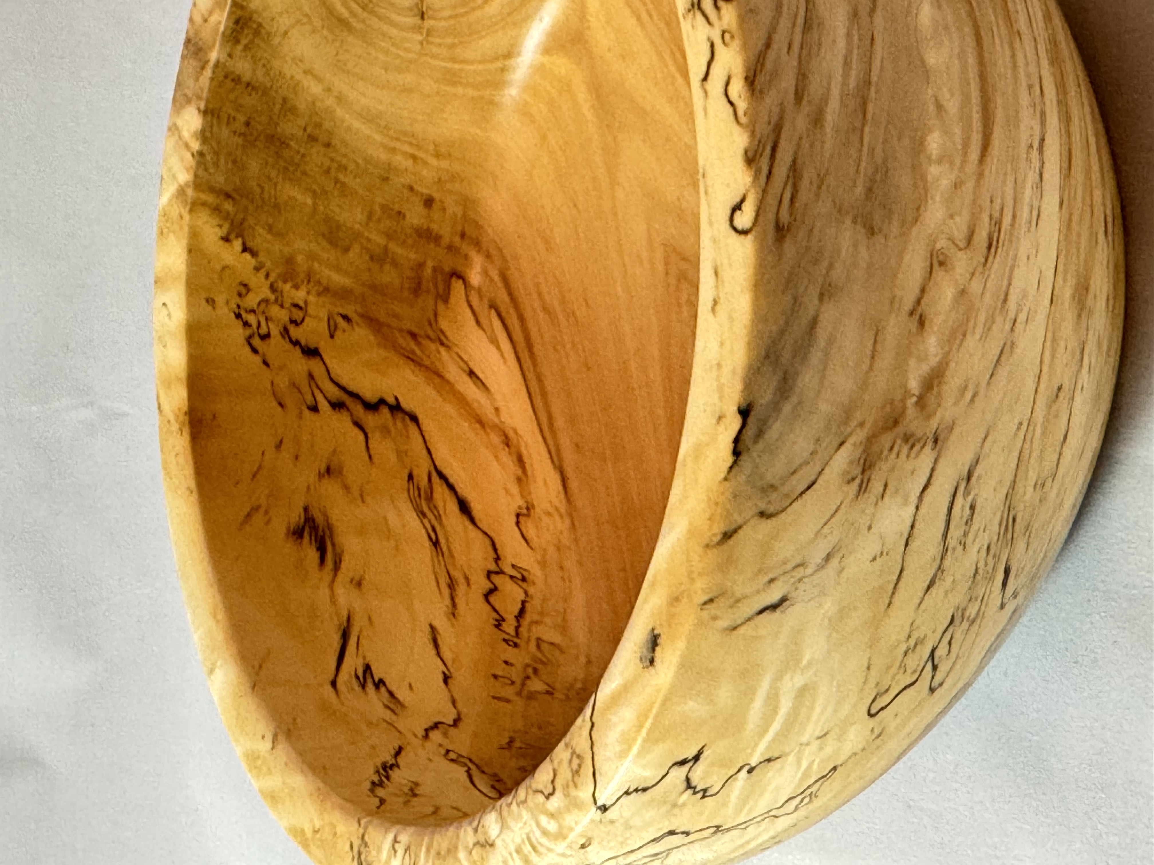 Side view of a smaller spalted maple bowl showing pale maple and black fungal figure